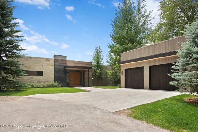 a brick house with a big yard and large trees