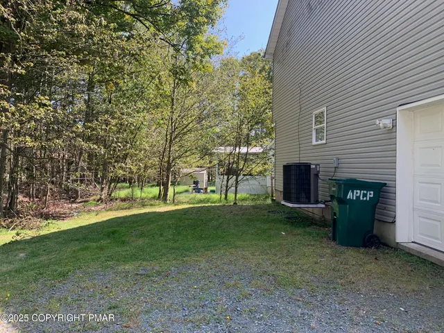 a view of a backyard with large trees and a small barn