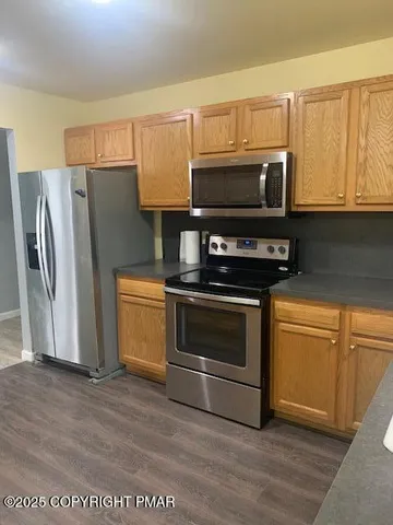 a kitchen with granite countertop a refrigerator stove and microwave