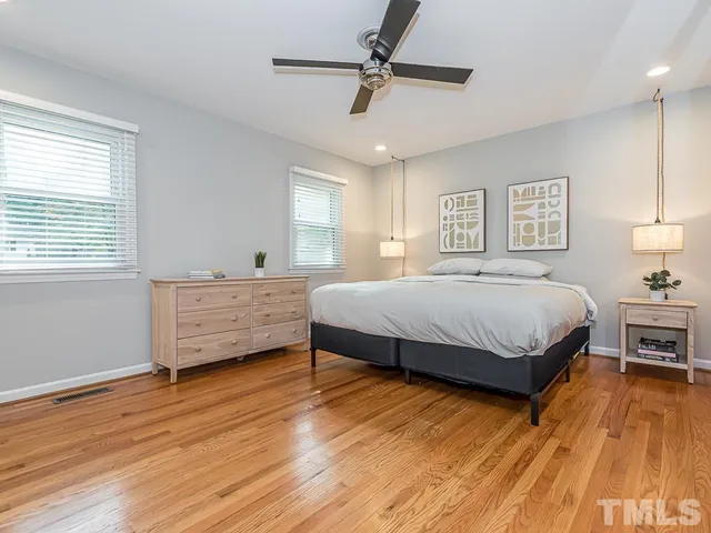 a spacious bedroom with a bed and wooden floor