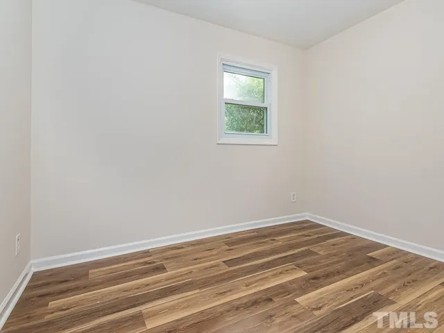 a view of a hallway with wooden floor and a bathroom