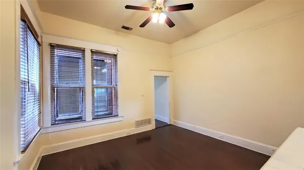 an empty room with wooden floor fan and windows