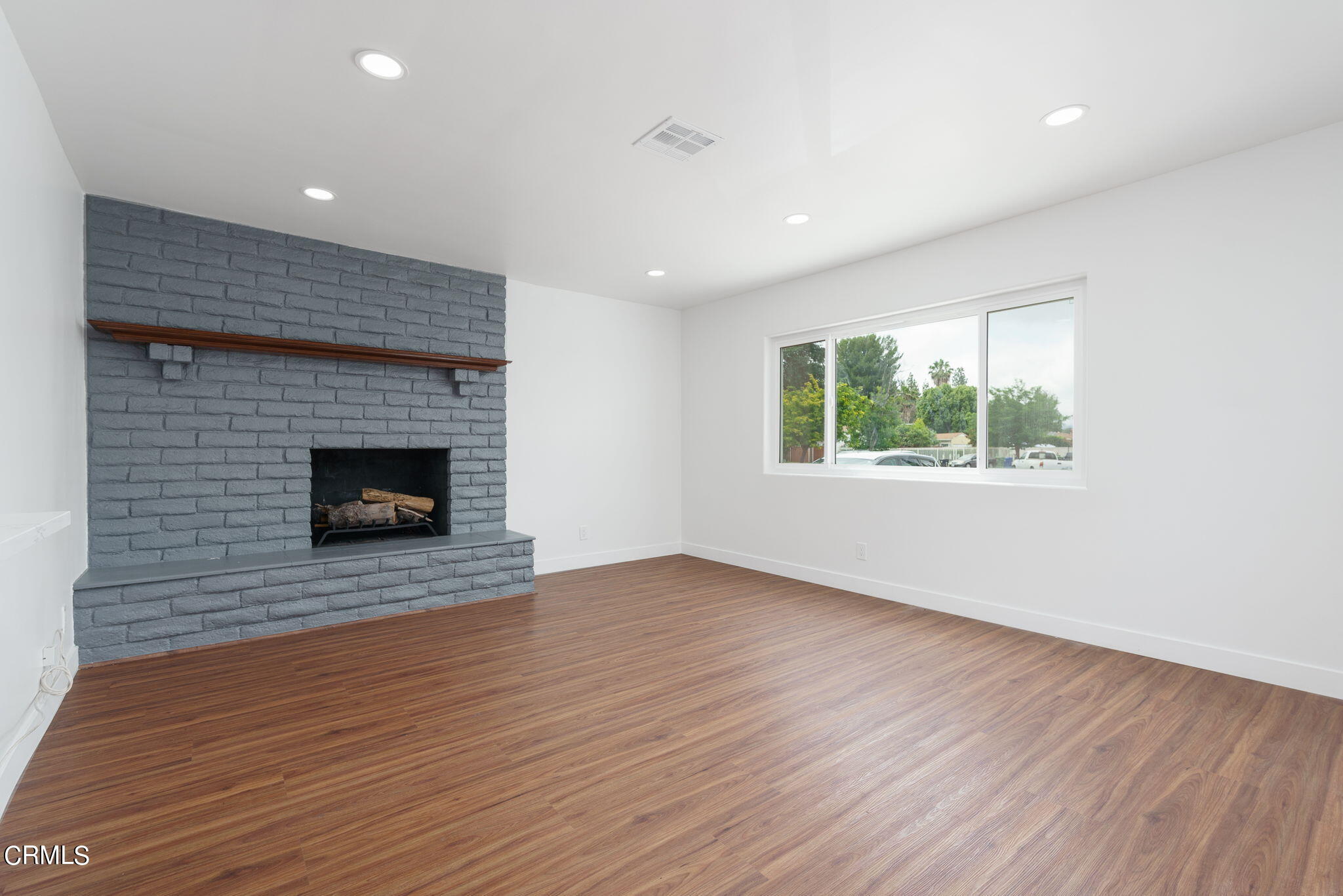 20205 Schoolcraft Street Winnetka, CA 91306 - Photo 12 of 22 an empty room with wooden floor fireplace and windows