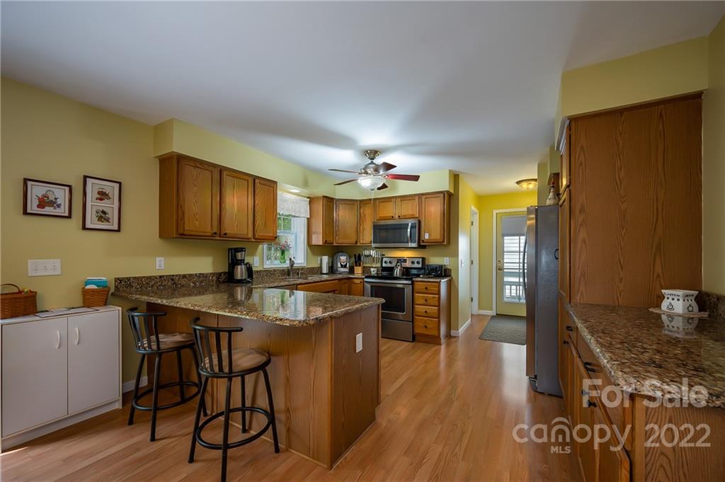 486 Groves Road Rutherfordton, NC 28139 - Photo 8 of 47 a kitchen with stainless steel appliances granite countertop a stove top oven a sink dishwasher a dining table and chairs with wooden floor