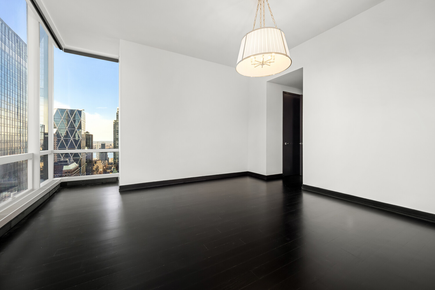 157 West 57th Street, Unit 43B Manhattan, NY 10019 - Photo 6 of 10 an empty room with wooden floor and windows