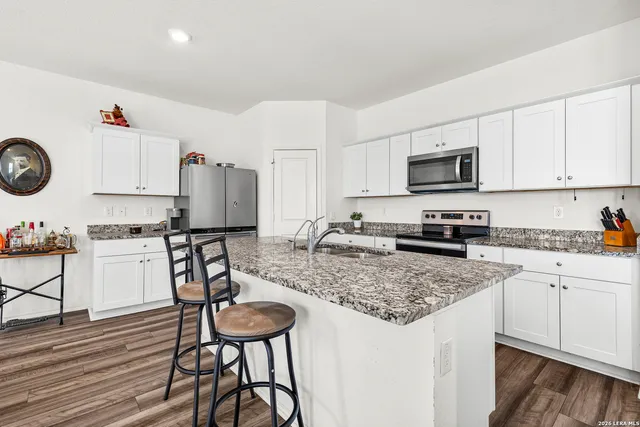 a kitchen with granite countertop a sink stove and white cabinets