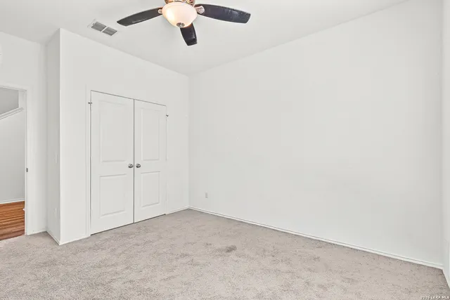 an empty room with a ceiling fan and carpet