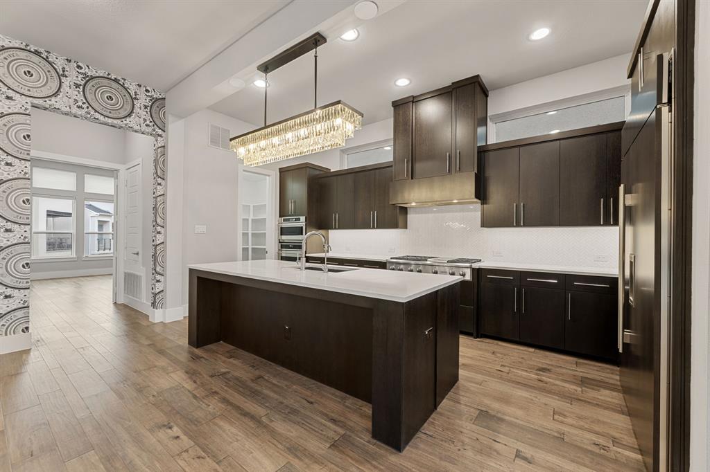 7854 Element Avenue Plano, TX 75024 - Photo 3 of 38 Kitchen with modern cabinets, an island with sink, light wood-style flooring, and backsplash