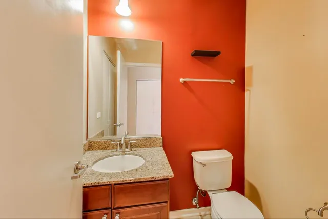 a bathroom with a granite countertop toilet a sink and a mirror