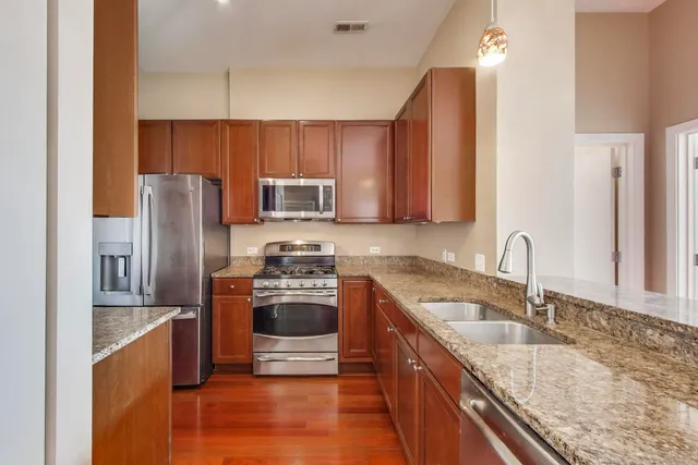 a kitchen with stainless steel appliances granite countertop a sink stove and refrigerator