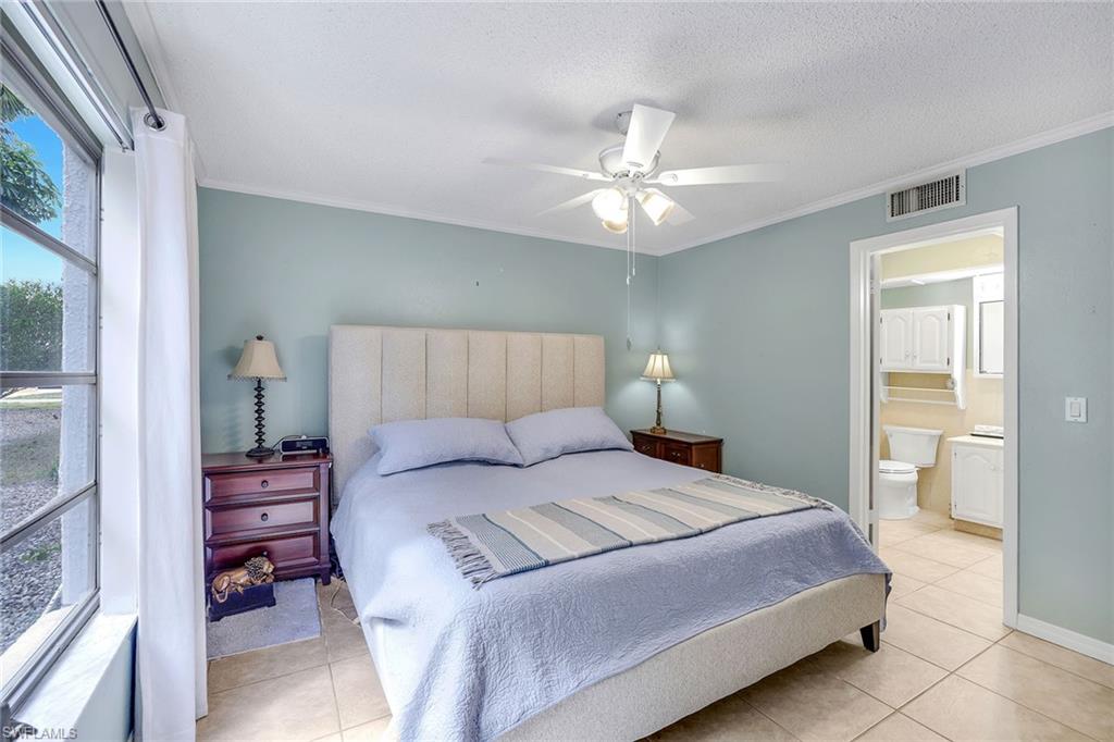 12 Watercolor Way, Unit 12 Naples, FL 34113 - Photo 19 of 35 a bedroom with a bed and a chandelier