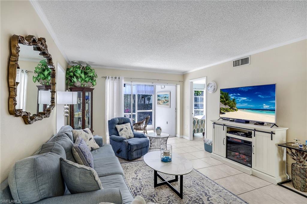 12 Watercolor Way, Unit 12 Naples, FL 34113 - Photo 8 of 35 a living room with furniture a flat screen tv and a fireplace
