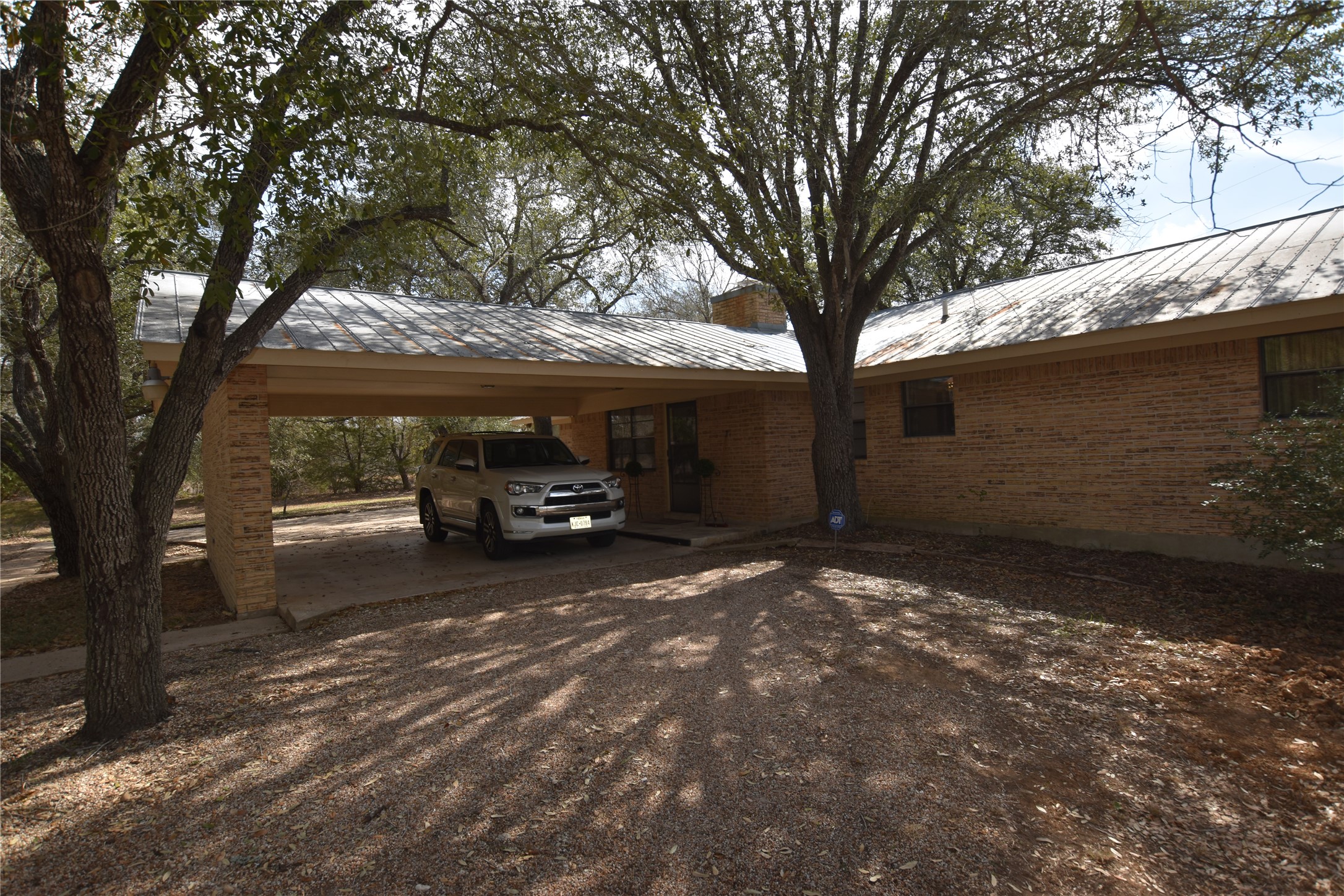 687 Fm 812 Road Red Rock, TX 78662 - Photo 1 of 40 View of parking featuring a carport and dirt driveway. Roof with new shingles on 3.17.2026.