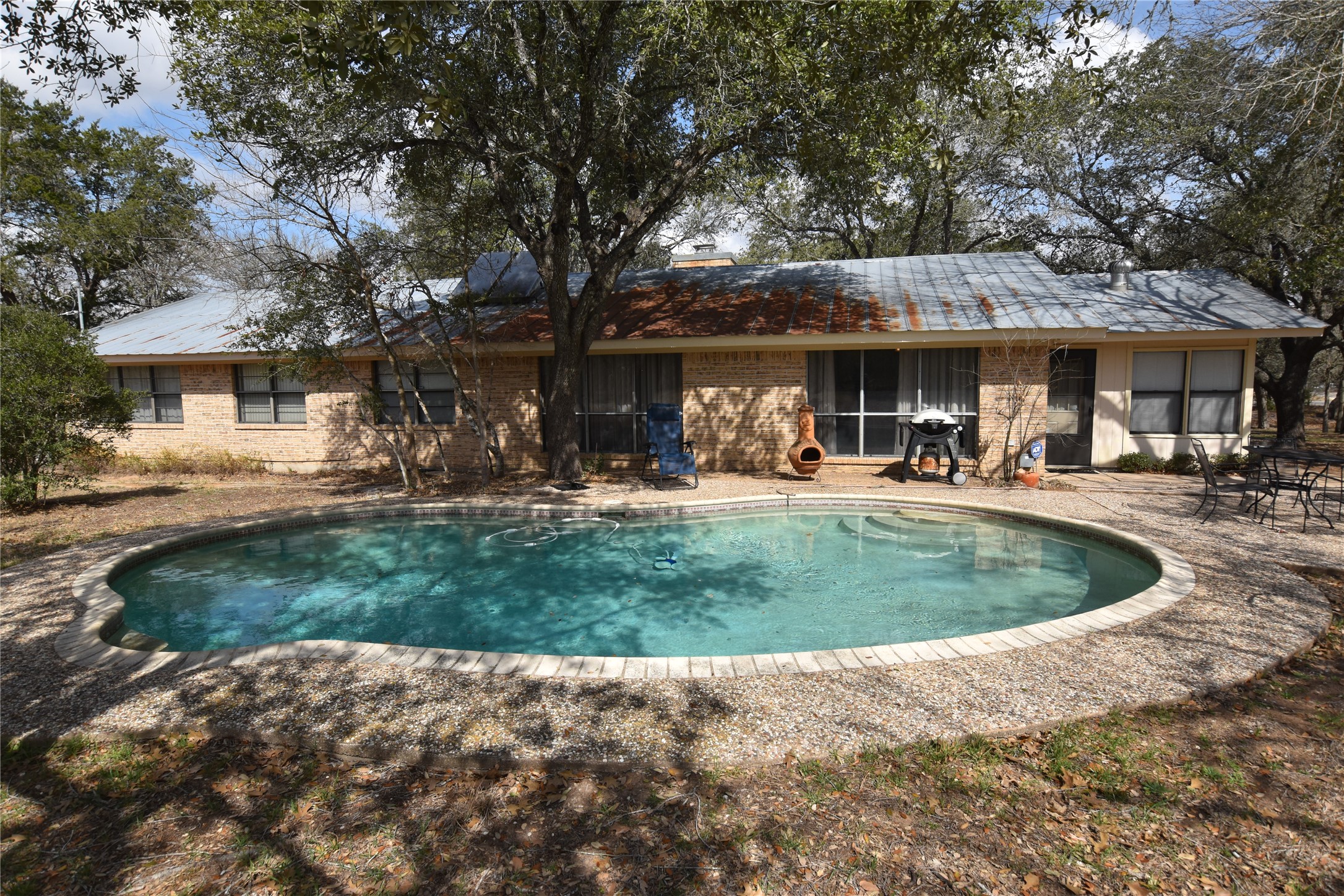 687 Fm 812 Road Red Rock, TX 78662 - Photo 21 of 40 Rear view of house featuring an outdoor pool, brick siding, and a patio
