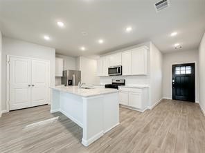 52 Valiant Ridge Trail Magnolia, TX 77354 - Photo 5 of 16 a kitchen with white cabinets and stainless steel appliances