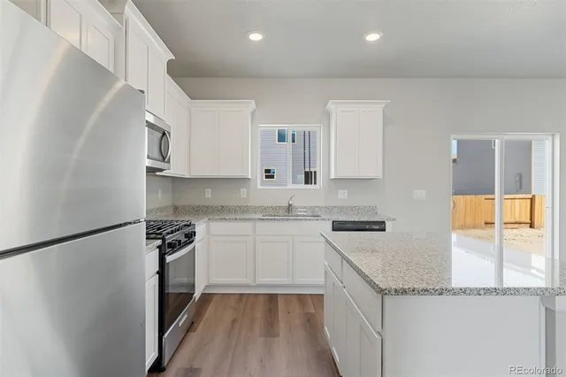 a kitchen with granite countertop a sink stove and refrigerator