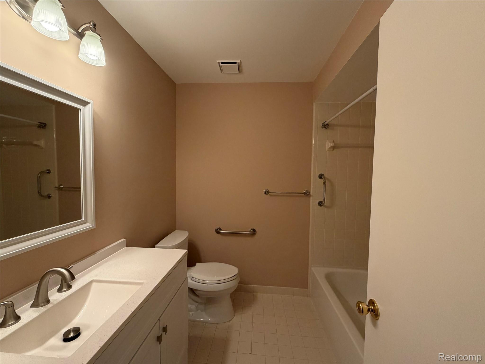 5220 West Utica Road Utica, MI 48317 - Photo 18 of 24 Bathroom featuring a white vanity with integrated sink, brushed nickel faucet, framed mirror, and overhead lighting