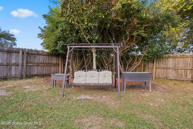 a view of backyard with table and chairs and a large tree