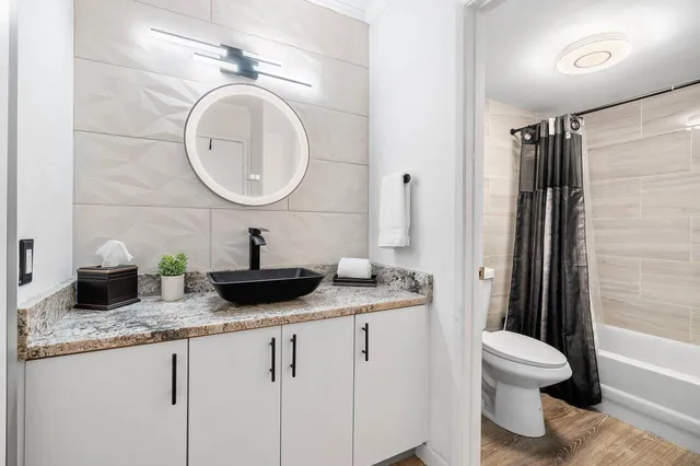 a bathroom with a granite countertop sink a toilet and a mirror
