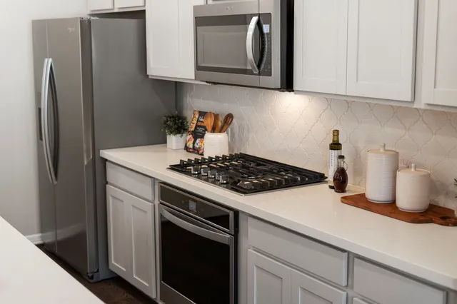 a kitchen with a sink a stove and chairs with wooden floor
