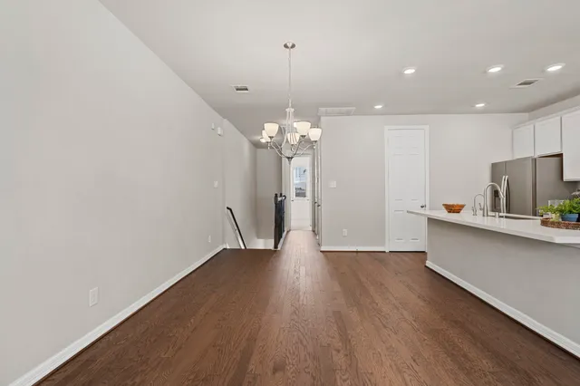 a kitchen with stainless steel appliances granite countertop a dishwasher a stove a microwave oven a sink dishwasher and white cabinets with wooden floor