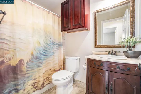 a bathroom with a granite countertop sink a toilet and a mirror