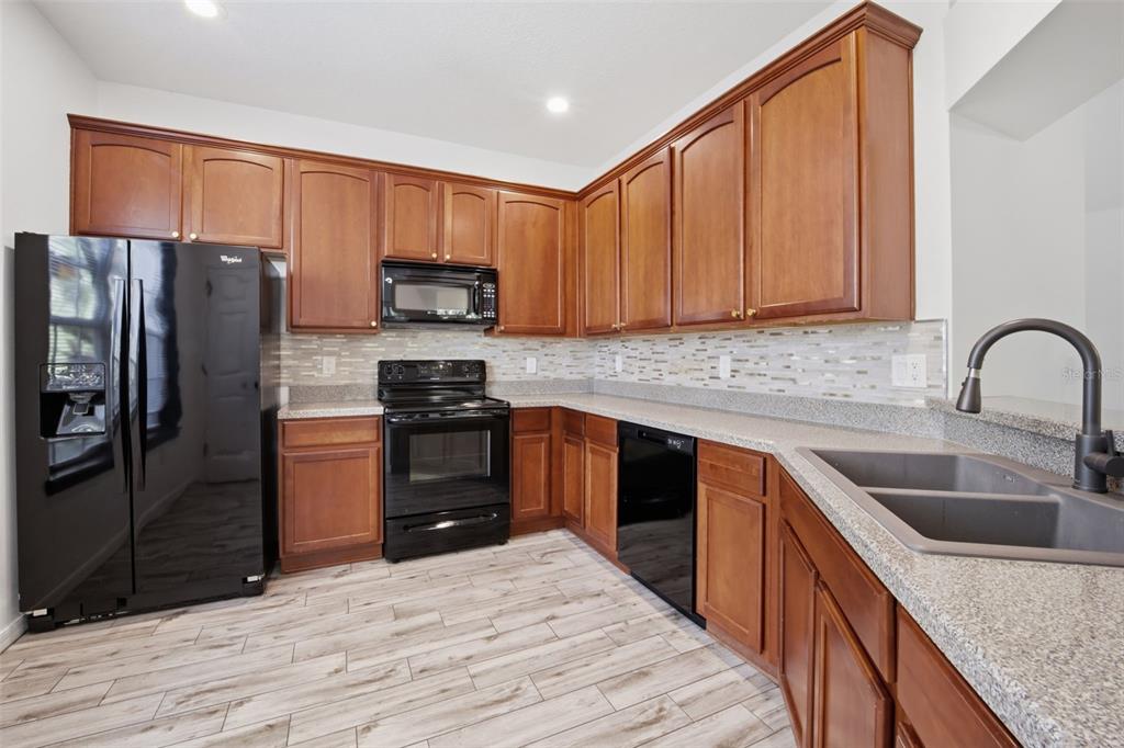 27547 Pleasure Ride Loop Wesley Chapel, FL 33544 - Photo 12 of 40 a kitchen with granite countertop a refrigerator stove and sink