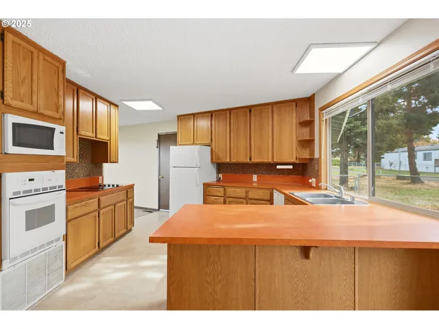 a kitchen with refrigerator a stove a sink dishwasher and wooden cabinets with wooden floor