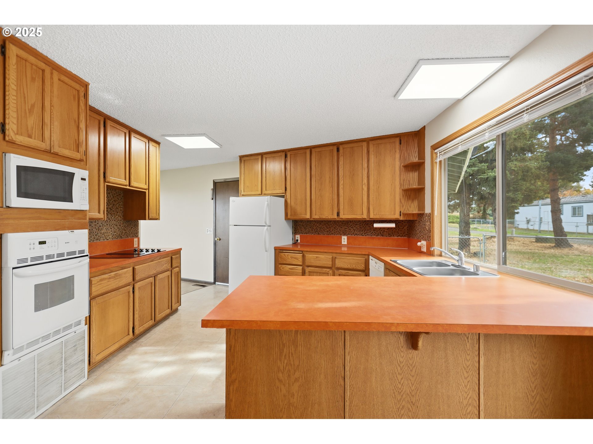 512 6th Street Wasco, OR 97065 - Photo 12 of 45 a kitchen with refrigerator a stove a sink dishwasher and wooden cabinets with wooden floor