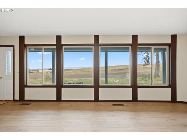 a view of an empty room with wooden floor and windows