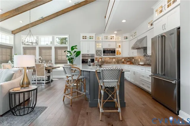 a kitchen with stainless steel appliances a dining table chairs refrigerator and sink