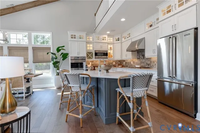 a kitchen with stainless steel appliances granite countertop a stove a refrigerator a kitchen island a table and chairs in it