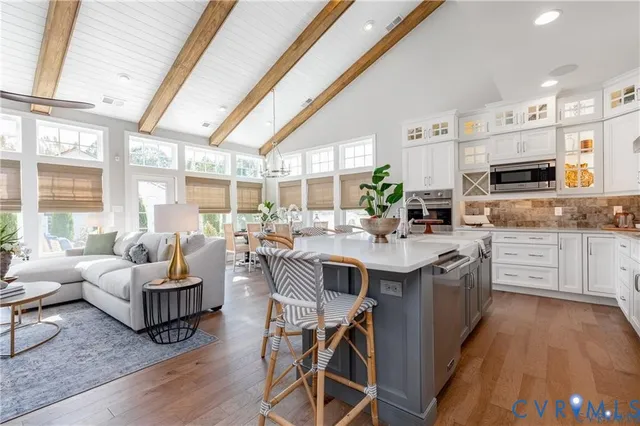 a living room with stainless steel appliances kitchen island granite countertop a dining table chairs and a large window