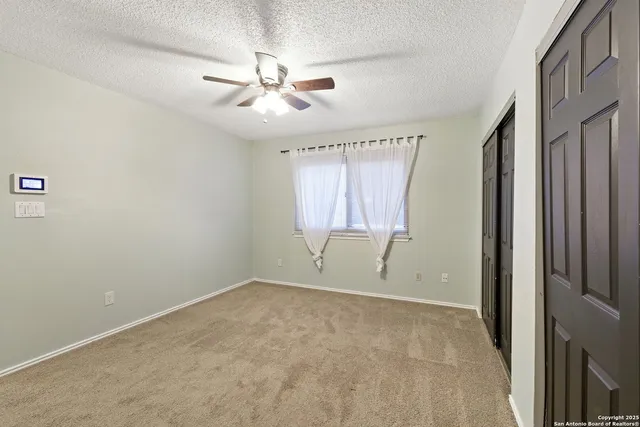 an empty room with windows and fan