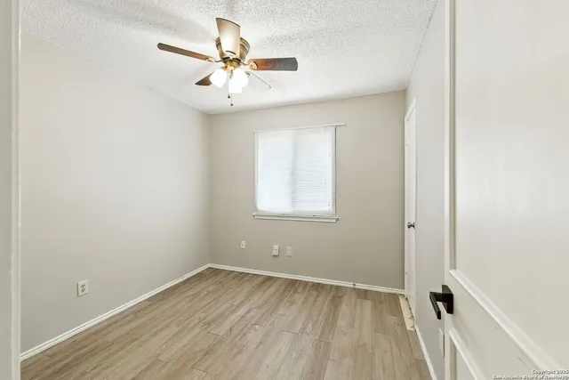 an empty room with a window and a fan