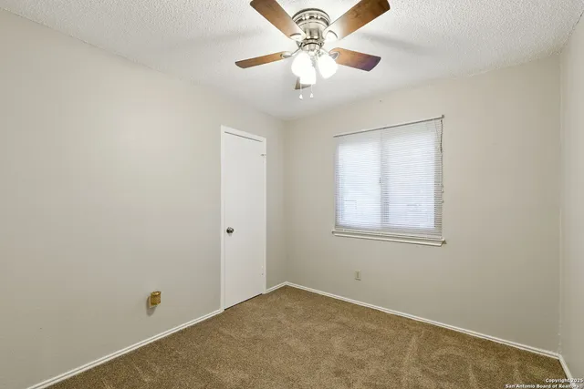 an empty room with a window and a fan