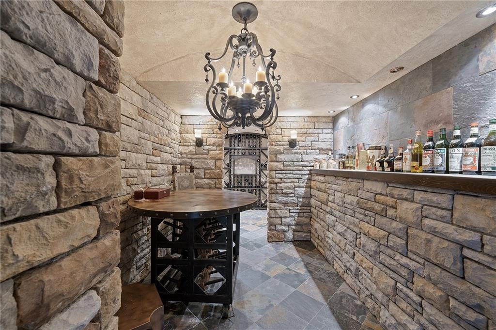 898 Persimmon Road Sewickley, PA 15143 - Photo 40 of 50 This wine cellar exudes old-world charm with stone walls, arched entryways, and a warm, softly lit ambiance. Slate floors, custom bottle storage, and a rustic chandelier create an inviting space for tastings and entertaining.