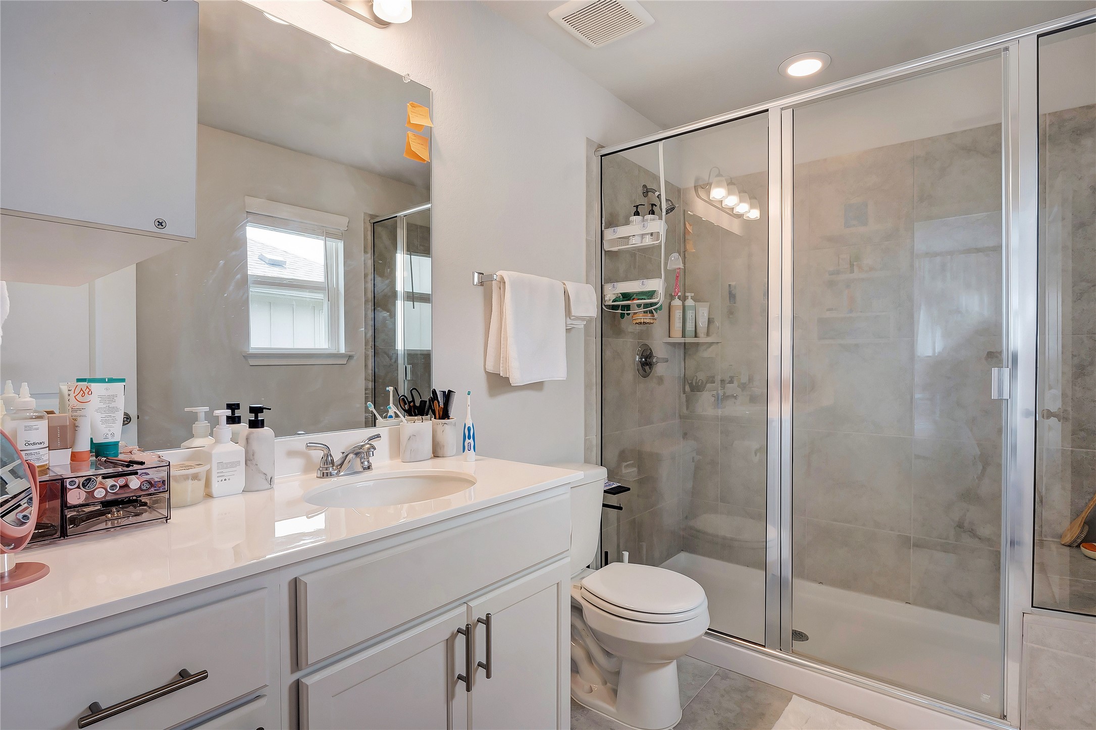 6554 Marsh Lane Buda, TX 78610 - Photo 14 of 30 a bathroom with a shower sink vanity mirror and toilet