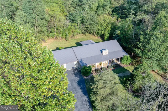 an aerial view of residential house with outdoor space and trees all around