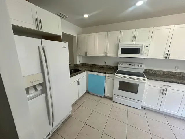 a kitchen with white cabinets and white appliances