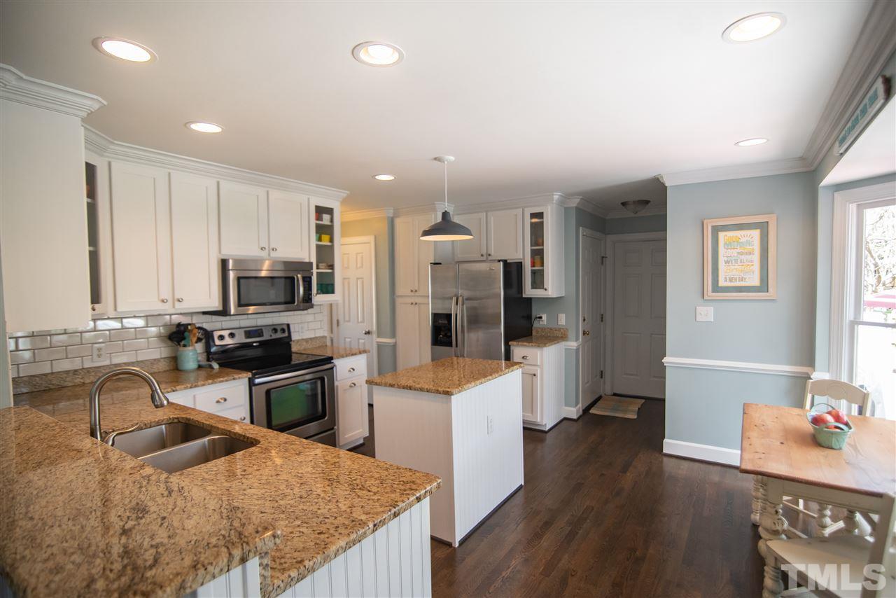 9116 Dawnshire Road Raleigh, NC 27615 - Photo 12 of 30 a kitchen with stainless steel appliances granite countertop a refrigerator a stove top oven a sink dishwasher and wooden cabinets with wooden floor