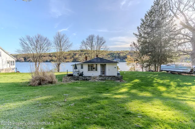 a view of a white house in a big yard with large trees