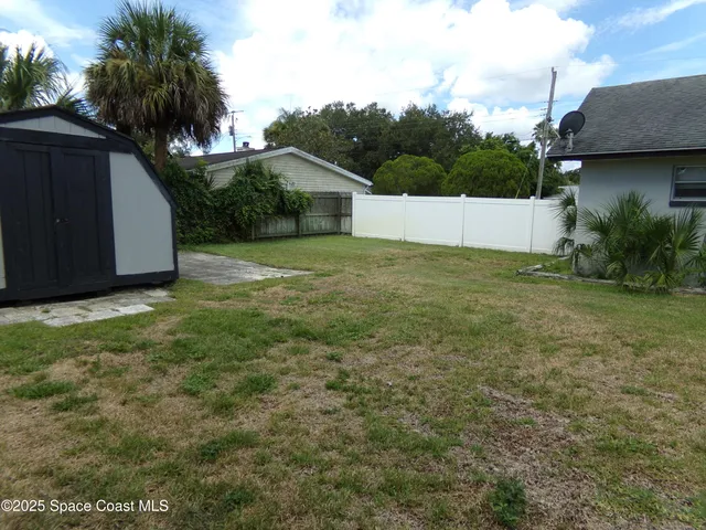 a backyard of a house with plants and palm trees