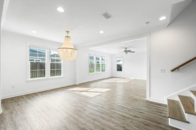 a view of empty room with wooden floor and chandelier