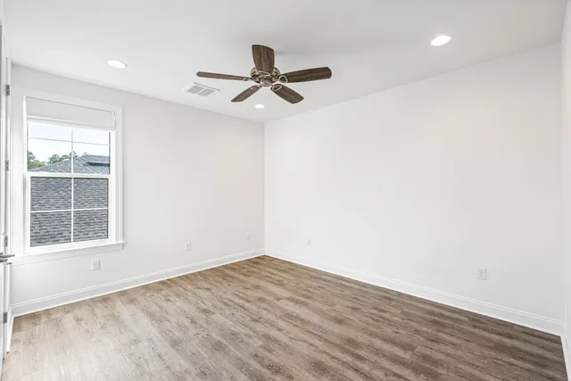 an empty room with wooden floor closet and windows