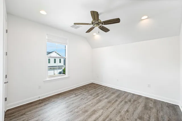 an empty room with wooden floor and ceiling fan