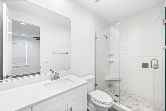 an empty room with wooden floor a ceiling fan and windows