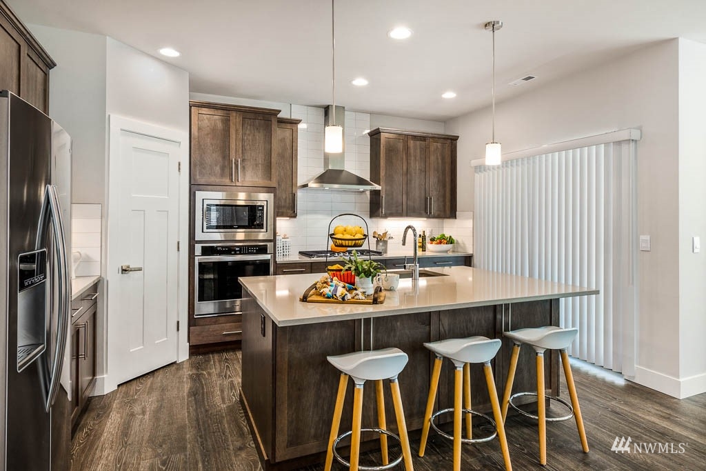 609 215th Street Southeast, Unit RM23 Bothell, WA 98021 - Photo 9 of 23 a kitchen with stainless steel appliances kitchen island granite countertop a dining table chairs refrigerator and sink