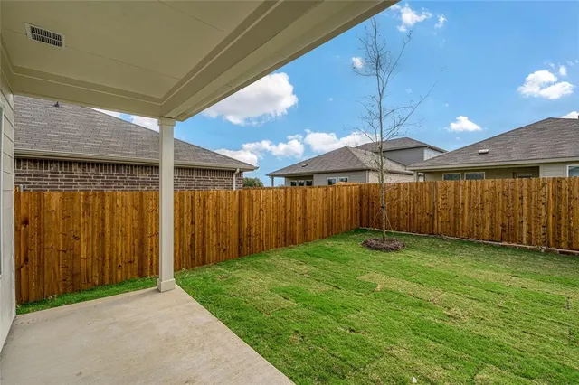 a view of a backyard with plants and wooden fence