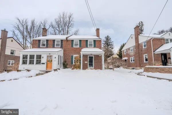a front view of a house with a yard covered in snow
